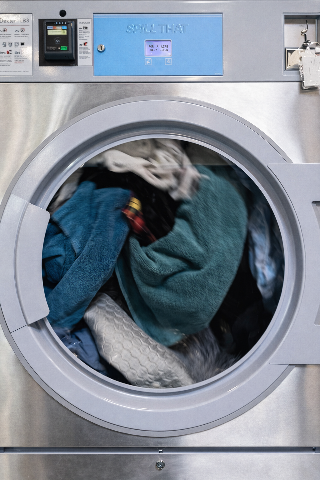 A Spill That branded washing machine mid-cycle, drum full of colourful laundry